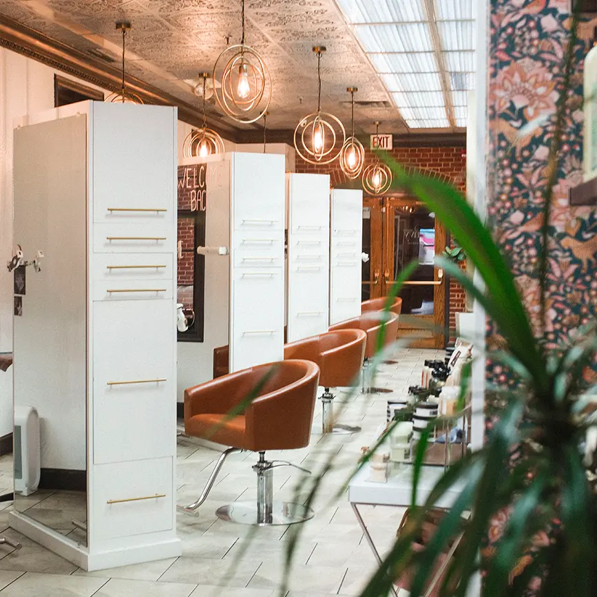 Stylish salon interior at Envy Studio featuring modern styling stations and warm lighting, inviting new clients to enjoy beauty services.