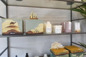 Boxes with desert-themed designs and containers of hair care products are displayed on metal shelves at Envy Studio Lancaster PA. | Envy Studio, Lancaster, PA