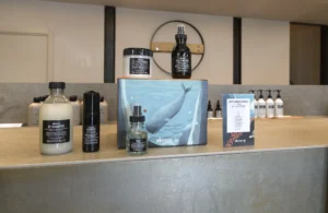A display of Davines hair care products, including shampoo, conditioner, and styling items, arranged on a counter with a whale-themed box and informational cards at Envy Studio Lancaster PA. | Envy Studio, Lancaster, PA